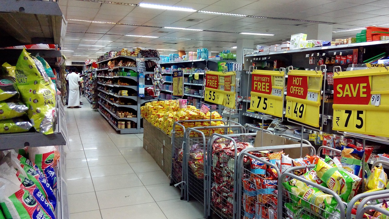 A shopper using a smartphone app to scan a product barcode in a supermarket aisle.