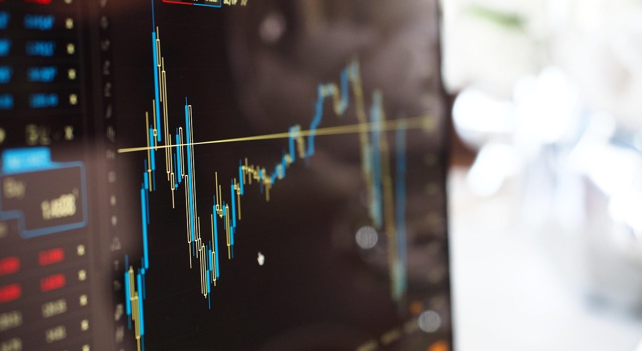 A close-up of shiny gold bars resting on top of a financial stock chart illustrating recent gold price trends.