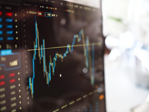 A close-up of shiny gold bars resting on top of a financial stock chart illustrating recent gold price trends.
